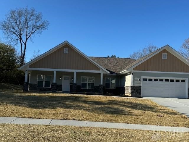 craftsman-style house with a porch, a front yard, and a garage