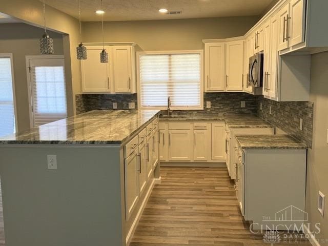 kitchen with white cabinets, decorative light fixtures, and light hardwood / wood-style flooring