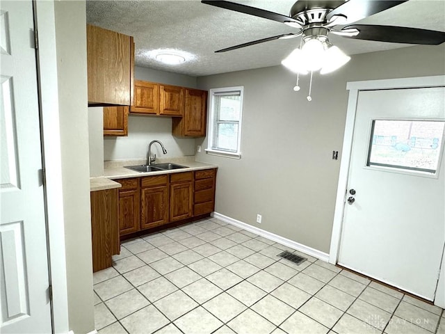 kitchen featuring ceiling fan, sink, light tile patterned floors, and a textured ceiling