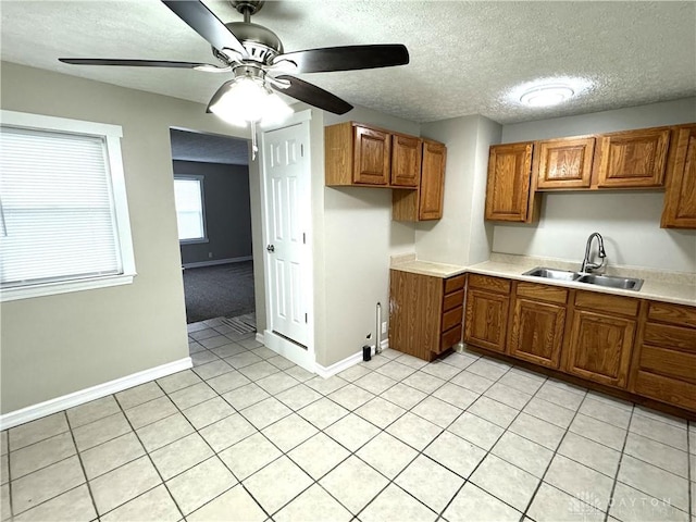 kitchen with a textured ceiling, ceiling fan, light tile patterned floors, and sink