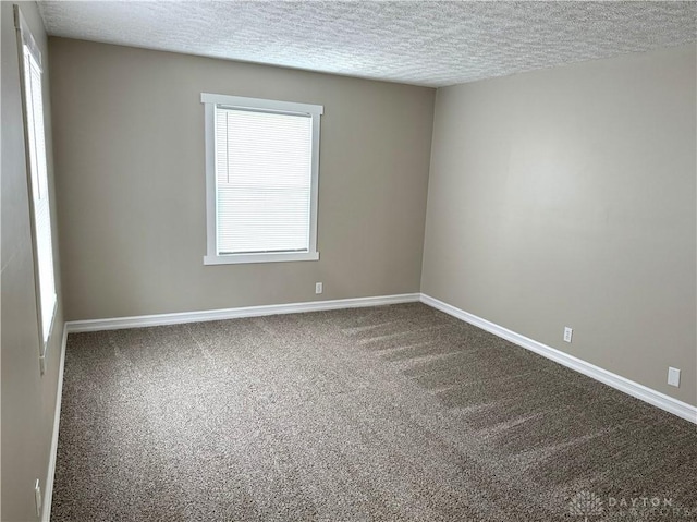 carpeted empty room with a textured ceiling