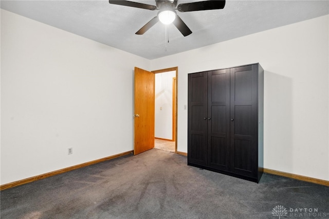 unfurnished bedroom featuring ceiling fan, dark carpet, and a closet