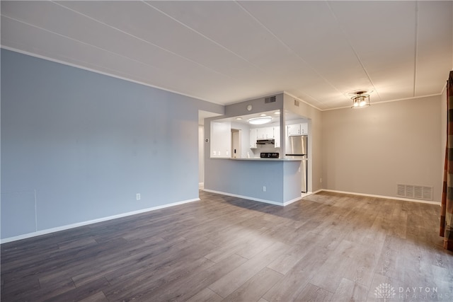 unfurnished living room featuring hardwood / wood-style floors and ornamental molding