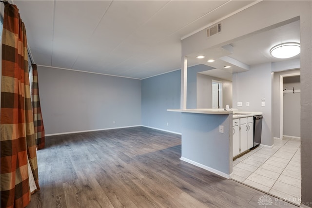 kitchen featuring kitchen peninsula, crown molding, light hardwood / wood-style flooring, dishwasher, and white cabinets