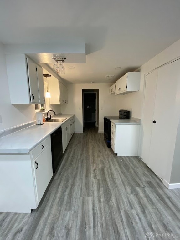 kitchen featuring white cabinets, black appliances, light wood-type flooring, and sink