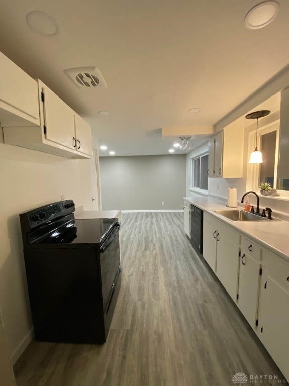 kitchen with sink, dark wood-type flooring, pendant lighting, white cabinets, and black appliances