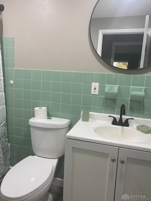 bathroom featuring vanity, tile walls, and toilet