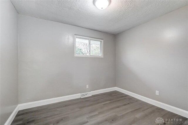 empty room with a textured ceiling and dark hardwood / wood-style floors