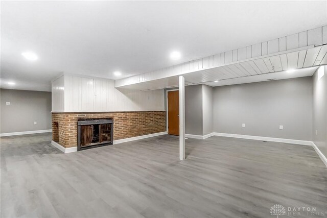 basement featuring hardwood / wood-style floors and a brick fireplace