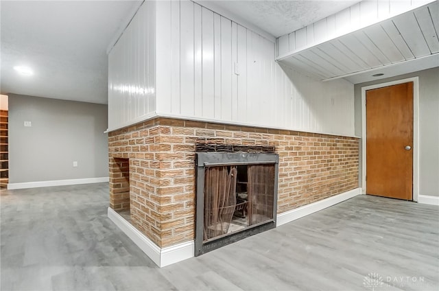 unfurnished living room with wood-type flooring and a brick fireplace