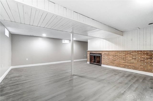 basement with hardwood / wood-style floors, brick wall, and a brick fireplace