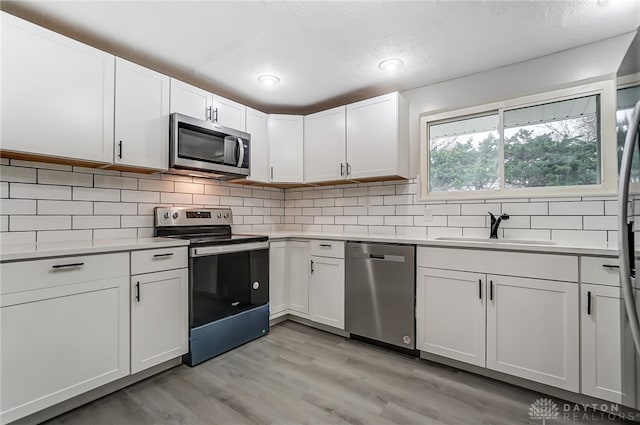 kitchen featuring light hardwood / wood-style flooring, stainless steel appliances, white cabinetry, and sink