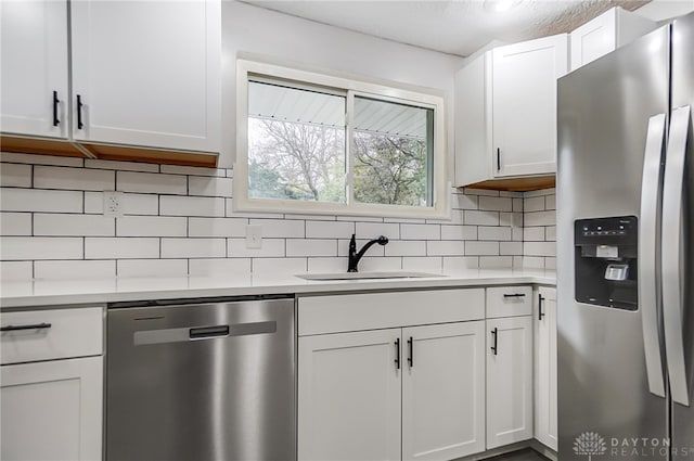 kitchen featuring white cabinets, stainless steel appliances, tasteful backsplash, and sink