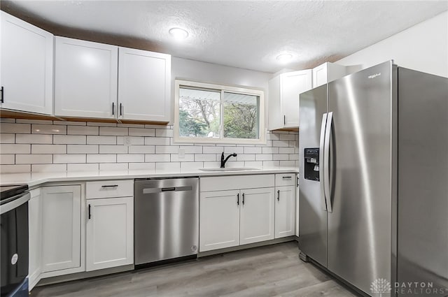 kitchen with decorative backsplash, appliances with stainless steel finishes, white cabinetry, and sink