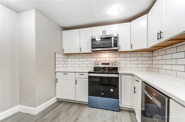 kitchen with white cabinets, backsplash, and appliances with stainless steel finishes