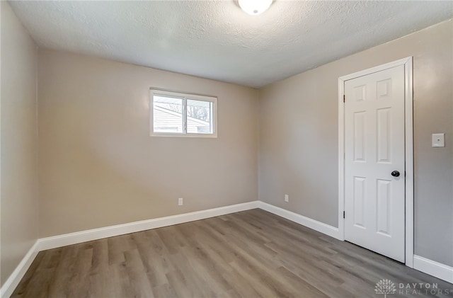 empty room with hardwood / wood-style floors and a textured ceiling