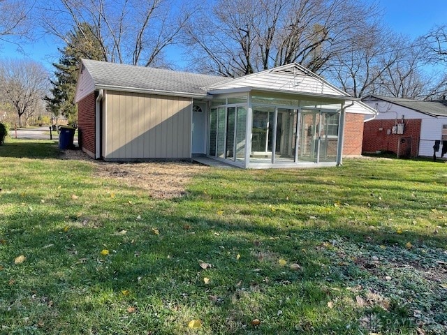 rear view of house featuring a sunroom and a yard