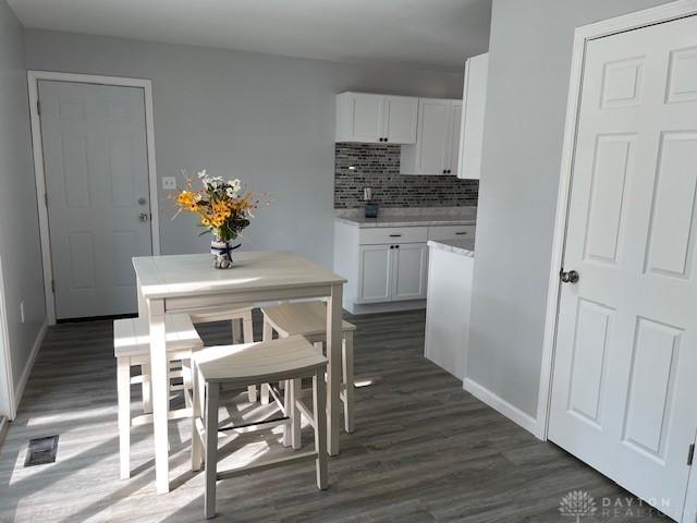 kitchen featuring backsplash, dark wood-type flooring, and white cabinets