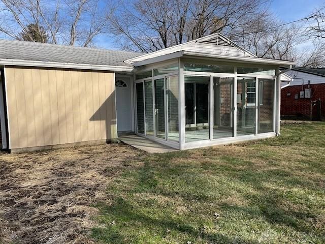 rear view of property featuring a yard and a sunroom