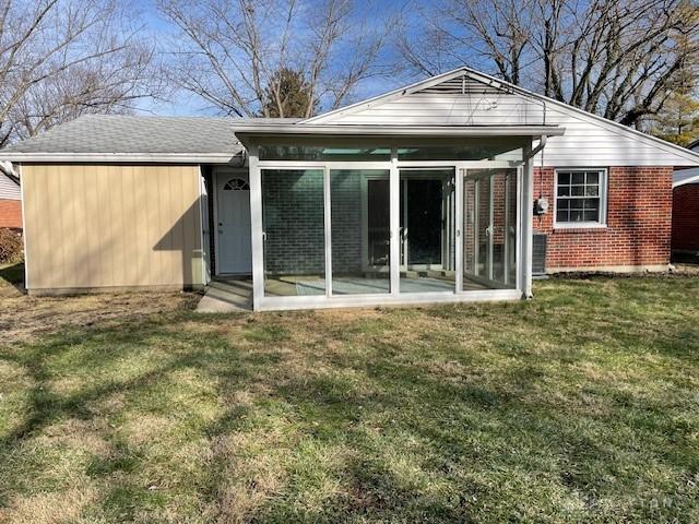 rear view of house featuring a sunroom and a lawn