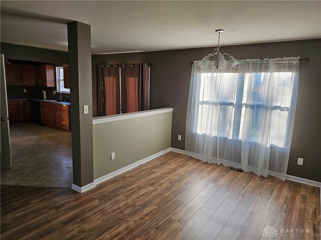 unfurnished dining area featuring a chandelier, sink, a wealth of natural light, and dark hardwood / wood-style flooring