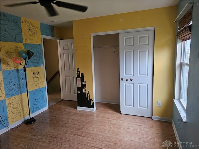 unfurnished bedroom featuring hardwood / wood-style flooring, ceiling fan, and a closet