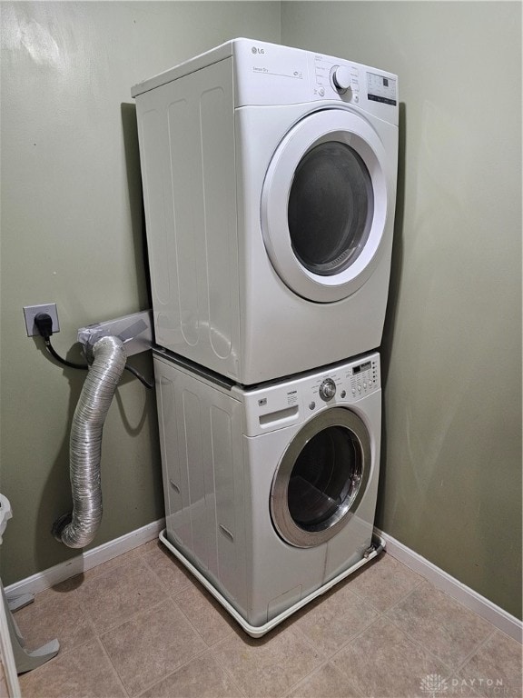 laundry room with light tile patterned flooring and stacked washing maching and dryer