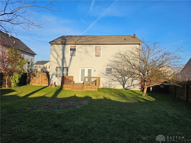 rear view of property with a wooden deck and a lawn