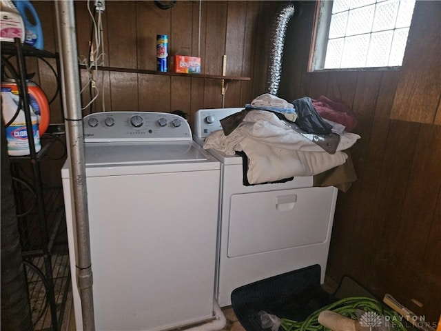 clothes washing area with washer and clothes dryer and wood walls