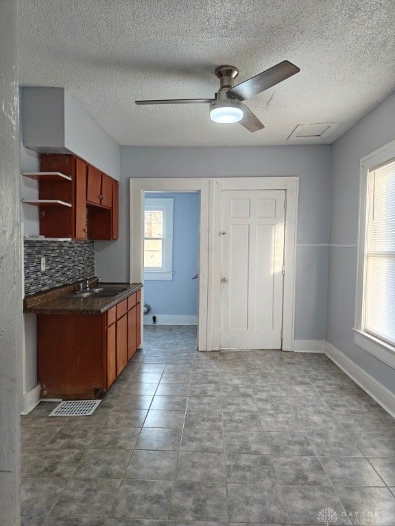 kitchen featuring tile patterned flooring, ceiling fan, decorative backsplash, and sink