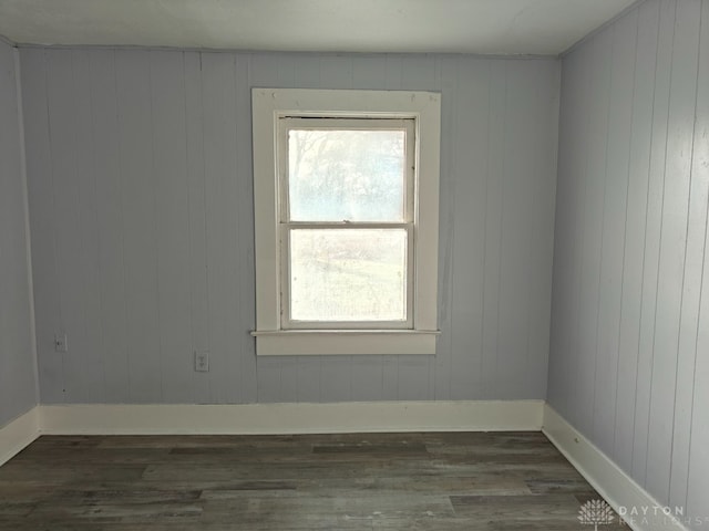 spare room featuring wood walls and dark hardwood / wood-style floors