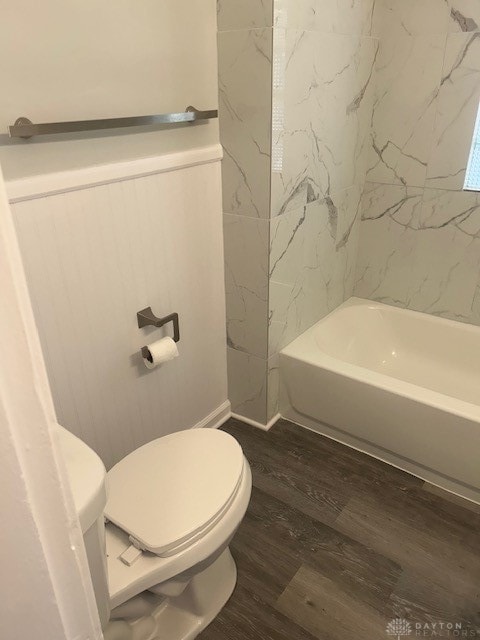 bathroom with tiled shower / bath, wood-type flooring, and toilet