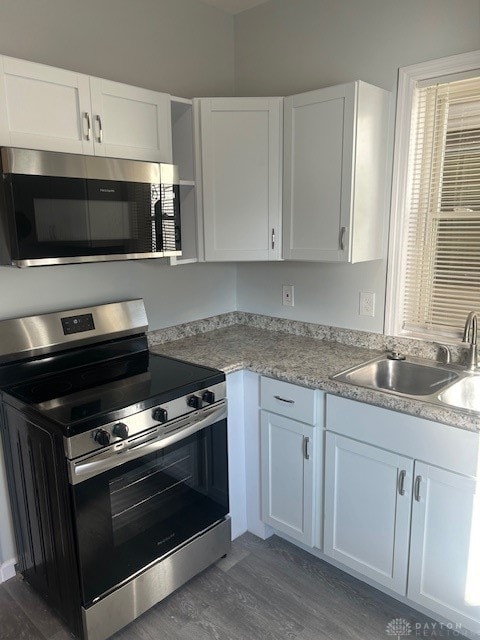 kitchen with sink, white cabinetry, dark wood-type flooring, and appliances with stainless steel finishes