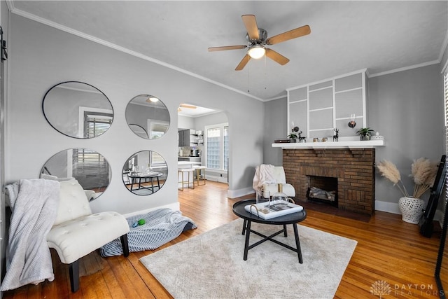 living room with arched walkways, ornamental molding, baseboards, and wood finished floors