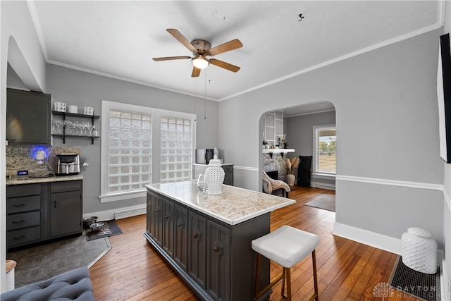 kitchen with decorative backsplash, dark hardwood / wood-style flooring, a kitchen island, and ceiling fan