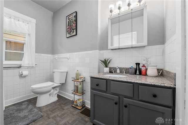 bathroom featuring toilet, vanity, tile walls, and parquet flooring