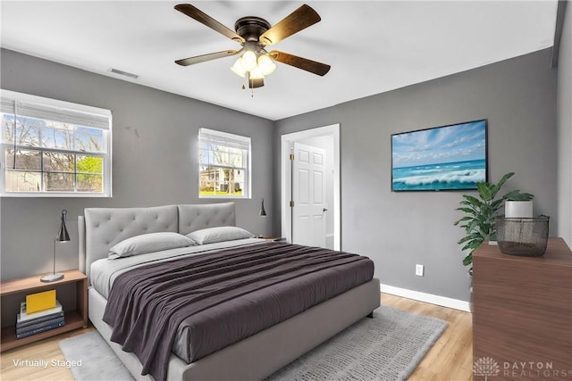 bedroom with multiple windows, hardwood / wood-style floors, and ceiling fan