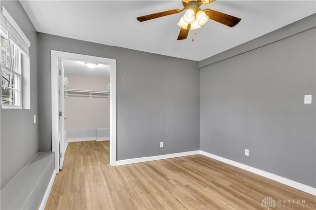 unfurnished bedroom featuring light hardwood / wood-style flooring, a walk in closet, a closet, and ceiling fan