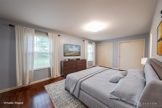 bedroom with dark hardwood / wood-style floors and multiple closets