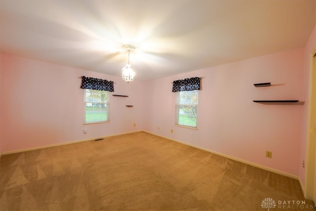 carpeted spare room featuring a notable chandelier