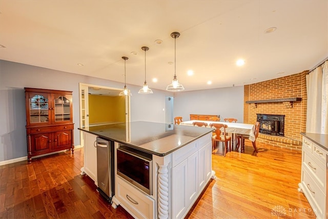 kitchen featuring white cabinetry, stainless steel microwave, pendant lighting, and light hardwood / wood-style floors