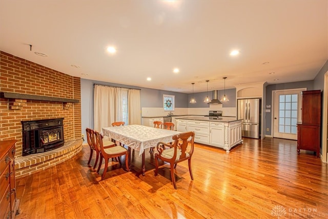 dining area featuring a brick fireplace and light hardwood / wood-style flooring