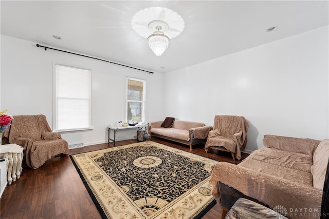 living room with dark hardwood / wood-style floors and an inviting chandelier