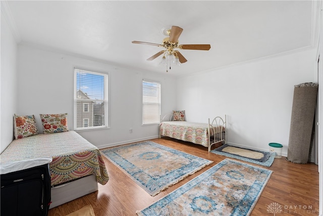 bedroom with hardwood / wood-style flooring, ceiling fan, and crown molding