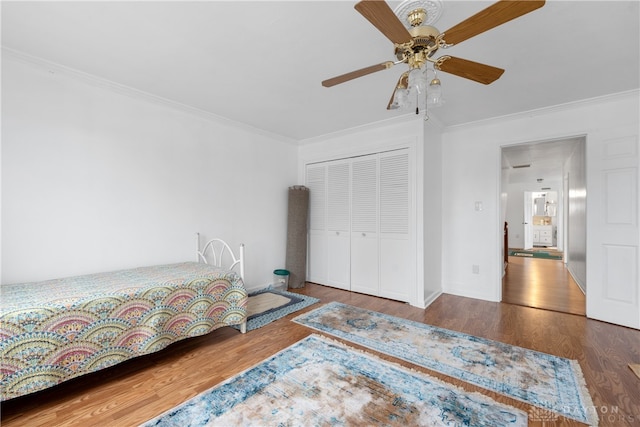 bedroom with a closet, hardwood / wood-style flooring, ceiling fan, and crown molding