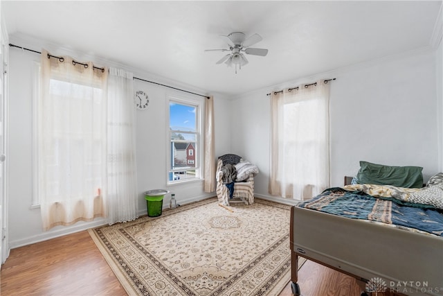 bedroom with hardwood / wood-style flooring, multiple windows, crown molding, and ceiling fan