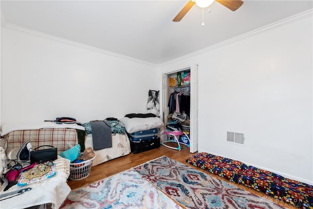 bedroom with a closet, ceiling fan, crown molding, and wood-type flooring