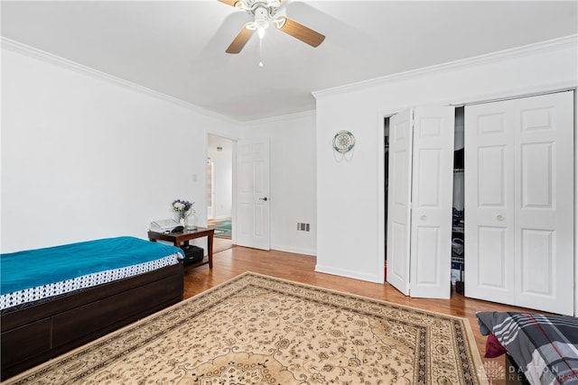 bedroom with wood-type flooring, ceiling fan, and crown molding