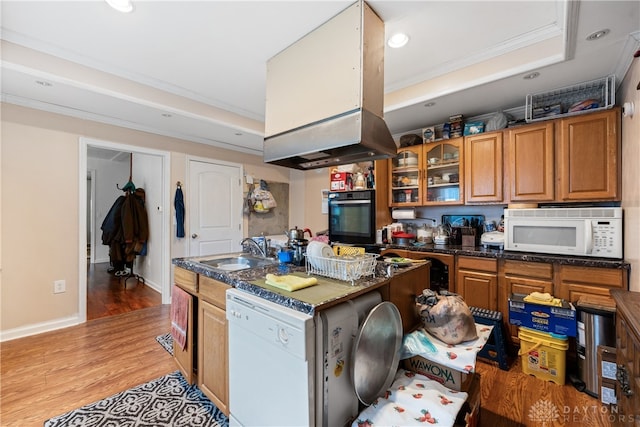 kitchen featuring white appliances, sink, a kitchen island, a tray ceiling, and light hardwood / wood-style floors