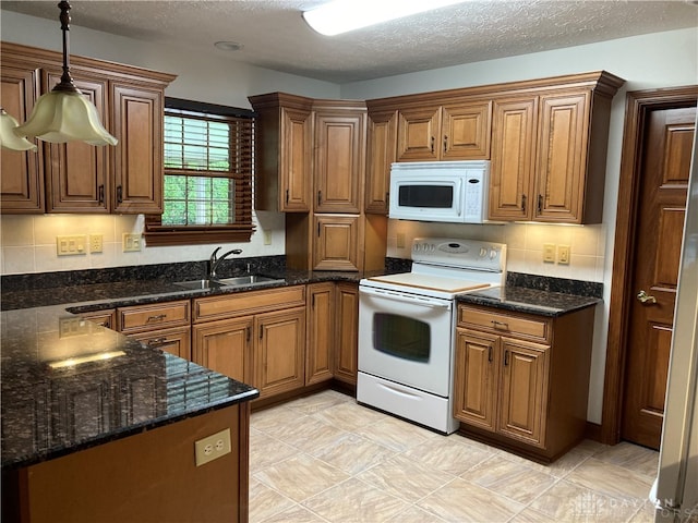 kitchen with pendant lighting, white appliances, sink, and tasteful backsplash